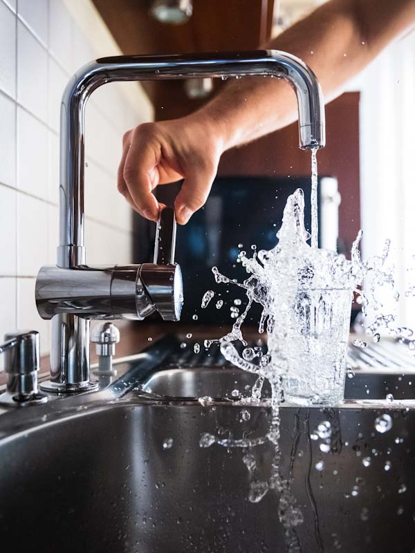 Overflowing cup of drinking water on a sink.